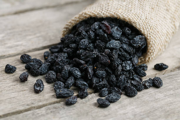 istock Black raisins in burlap bag over wooden gray table 1145879404