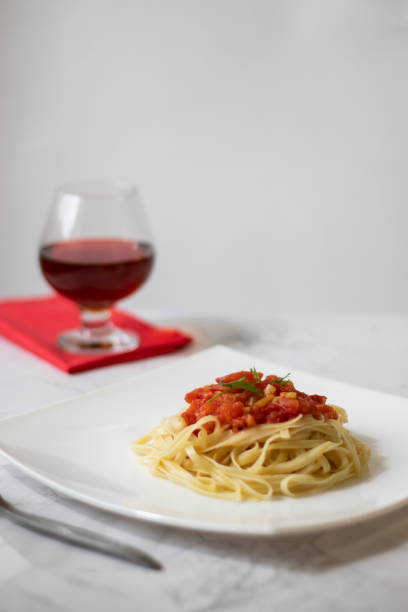 istock Pasta with fresh tomatoes, cooked with olive oil and garlic on a light background and a white square plate. Italian food. Vertical orientation 1145882408