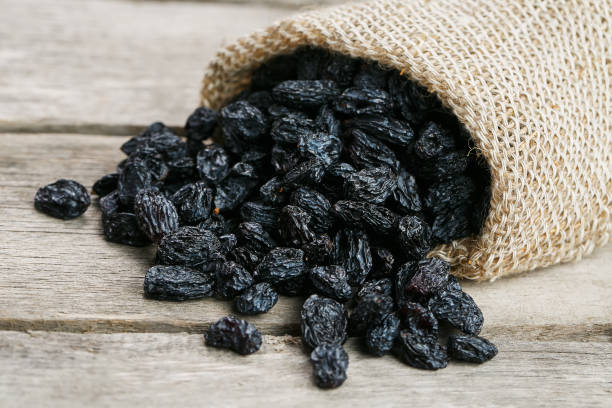 istock Black raisins in burlap bag over wooden gray table 1145882543