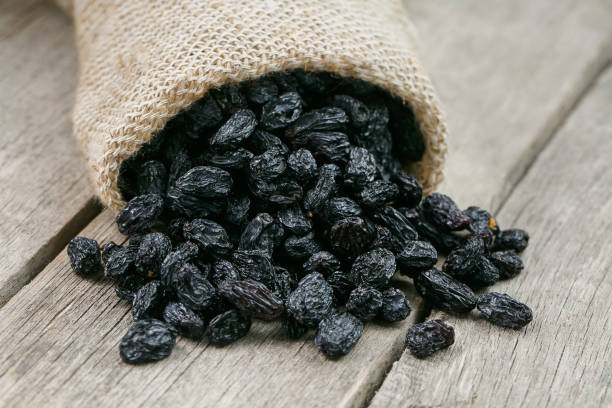 istock Black raisins in burlap bag over wooden gray table 1145882573
