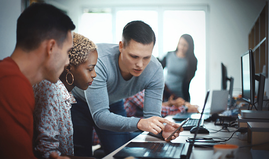 Closeup side view of group of mid 20's mobile application developers testing the code and fixing the issues.