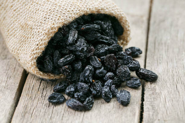 istock Black raisins in burlap bag over wooden gray table 1145883439
