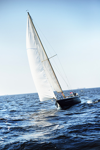 Blue yacht sailing close-hauled with full sails. Clear blue sky. Bay of Biscay, France