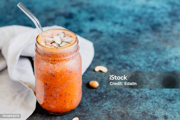 Orange And Purple Vegan Smoothie Is Made From Blueberry Sea Buckthorn Coconut Cream Nuts And Chia On A Blue Background The Concept Of Healthy Summer Food And Drink Stock Photo - Download Image Now