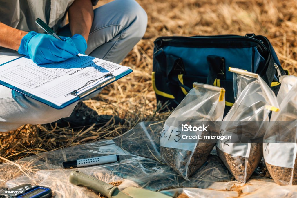 Soil Test. Female Agronomist Taking Notes In The Field Soil Test. Female agronomist taking notes in the field. Environmental protection, organic soil certification, research Geology Stock Photo