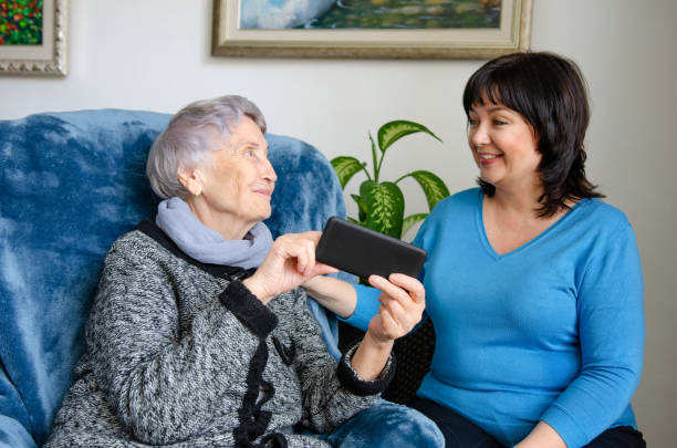 Female volunteer is happy to help an elderly woman use a smartphone stock photo