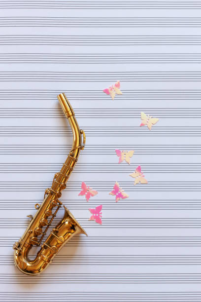 kleine goldene saxophon und glitzerfiguren. topansicht, nahaufnahme auf notenpapier hintergrund - close up musical instrument saxophone jazz stock-fotos und bilder