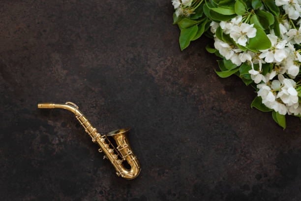 kleines goldenes saxophon und blühende apfelbaumzweige. topansicht, nahaufnahme auf weißem hintergrund - close up musical instrument saxophone jazz stock-fotos und bilder