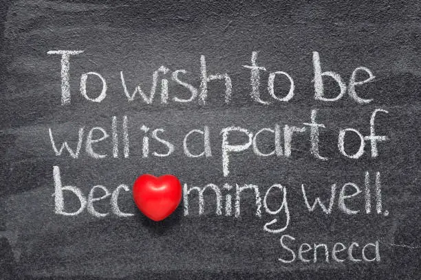 To wish to be well is a part of becoming well - quote of ancient Roman philosopher Seneca written on chalkboard with red heart instead of O