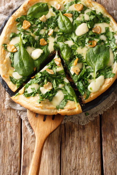istock Healthy white pizza with spinach, garlic and ricotta cheese and mozzarella close-up. Vertical top view 1145900385