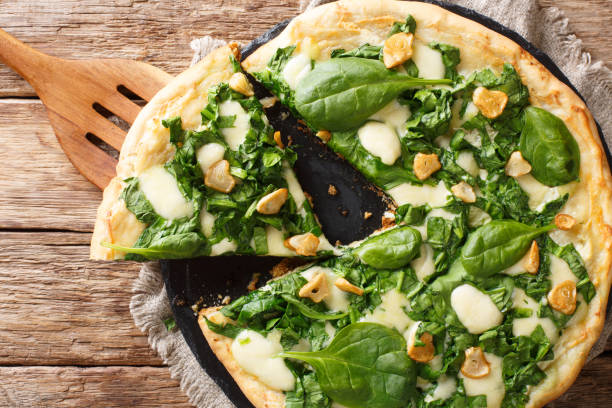 istock Delicious hot pizza with spinach, garlic and cheese close-up on the table. horizontal top view 1145900405