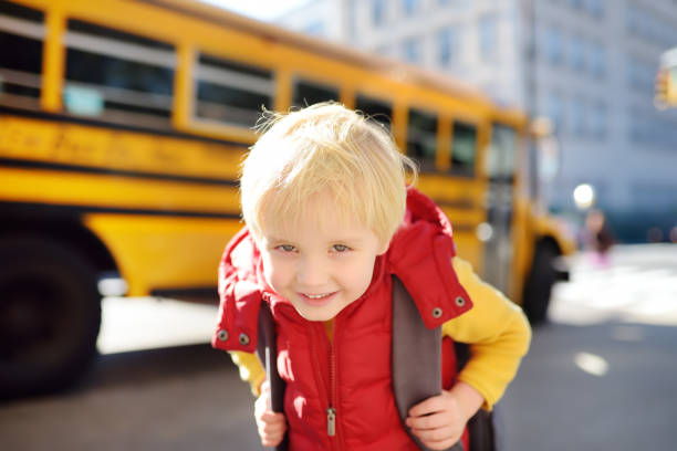 istock Pupil with schoolbag with yellow school bus on background. 1145902182