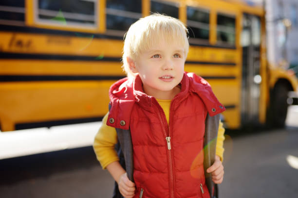 istock Pupil with schoolbag with yellow school bus on background. 1145902276
