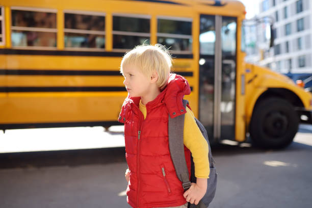istock Pupil with schoolbag with yellow school bus on background. 1145902361