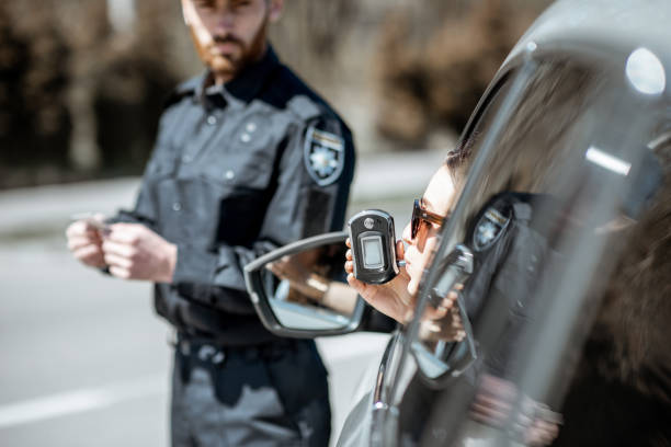 policeman checking woman driver for alcohol intoxication - intoxication imagens e fotografias de stock