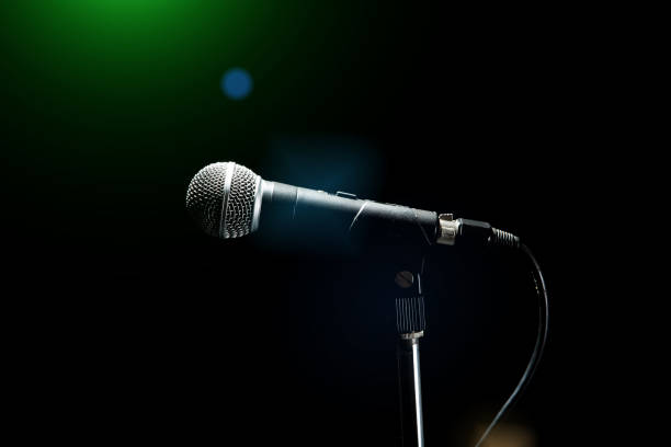 istock Black modern microphone on stand, black dark background. Accentuated shapes with light. 1145903742