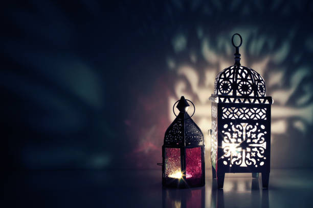 istock Moroccan ornamental lanterns on the table glowing at night. Greeting card, invitation for Muslim holy month Ramadan Kareem. Festive blue background with ornamental light and shadow play. 1145904588