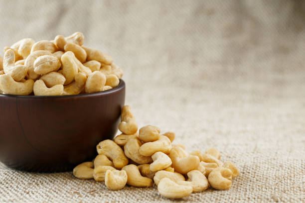 istock Cashew nuts in a wooden bowl on a burlap cloth background. 1145904764