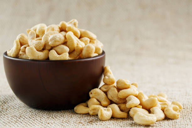istock Cashew nuts in a wooden bowl on a burlap cloth background. 1145906839