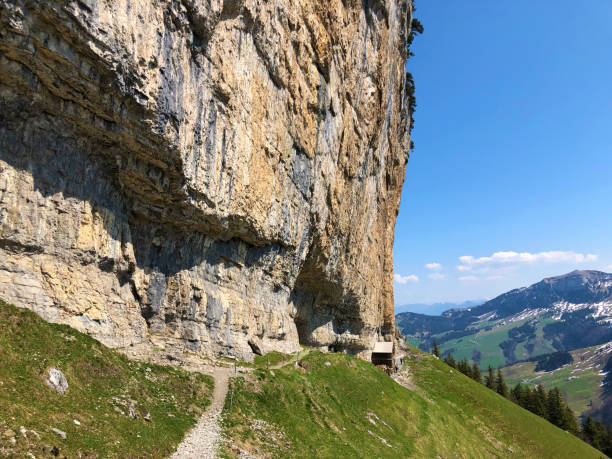 penhasco de äscher ou äscher-felsen (aescher-felsen ou ascher-felsen) na escala de montanha de alpstein e na região de appenzellerland - ascher - fotografias e filmes do acervo