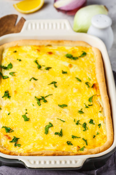 istock Onion pie with cheese and herbs in black baking dish. 1145908282