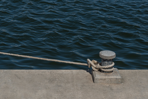 Rusty mooring bollard with ship ropes on seaport