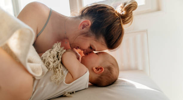 Cuddle Mom and baby boy cuddling on the bed in the morning garment photos stock pictures, royalty-free photos & images