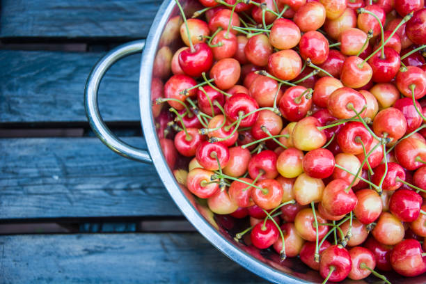 Cherries in a tin bowl on a wooden table - top view