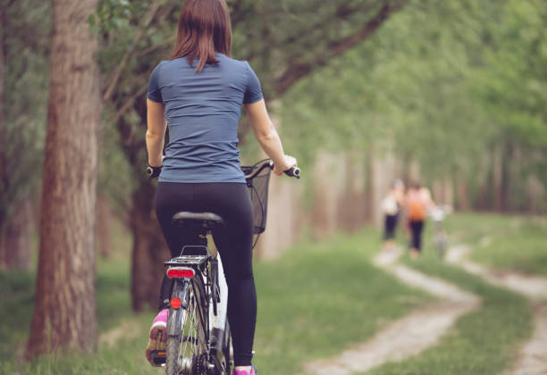istock Woman biker cycling in park from behind 1145924183