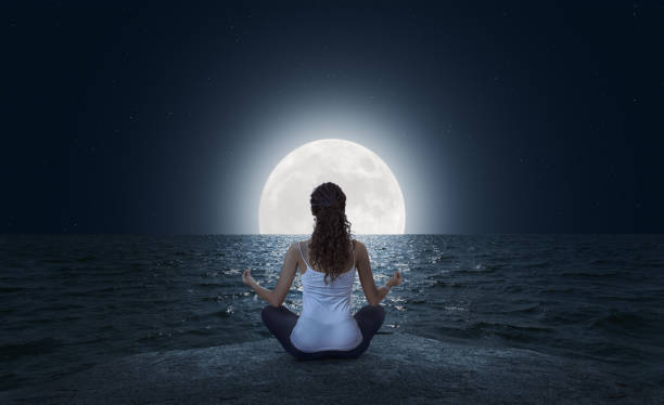 在滿月時在沙灘上冥想的年輕女子 - 夜晚 圖片 個照片及圖片檔
