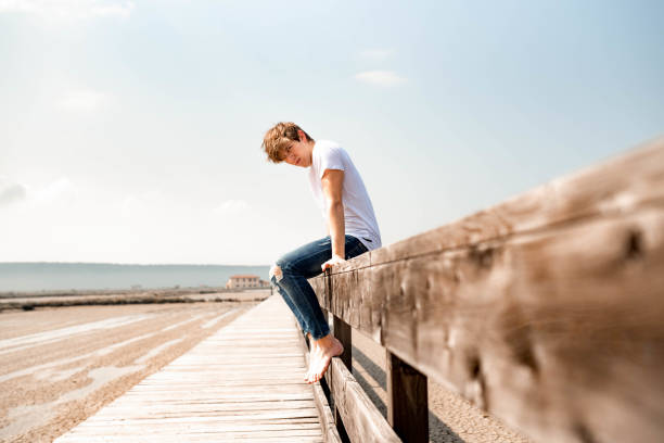 istock Young man sitting on a wooden fence 1145925686