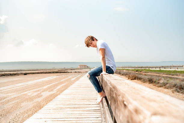 istock Young man sitting on a wooden fence 1145925694
