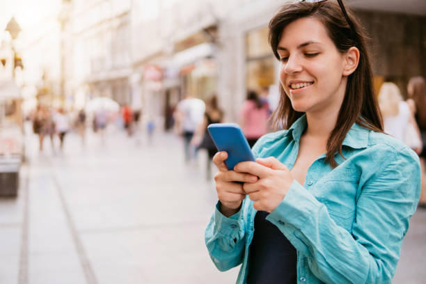 istock Young woman using phone on a city street 1145929286