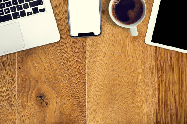 istock Mock up the office table seen from above. Flat lay smartphone, computer coffee and tablet on a wooden table. Copy space. Modern business in a classic edition. 1145933922