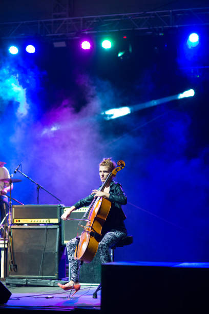 Young woman playing cello on the stage at the night concert.