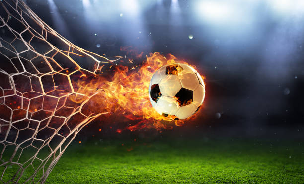 boule de soccer de feu dans l’objectif avec le filet dans les flammes - marquer un but photos et images de collection