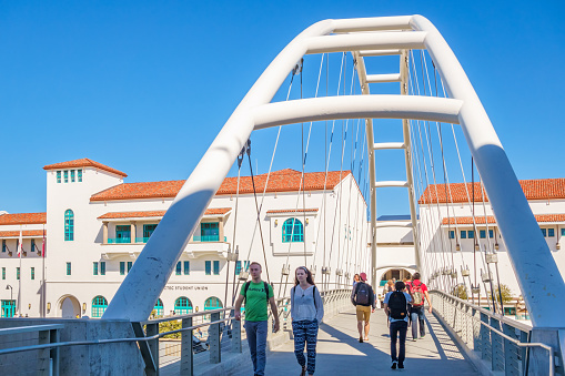 Students walk on a bridge at San Diego State University, California, USA on a sunny day.