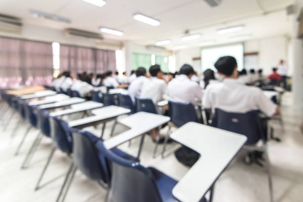 istock Blur school background back view university students writing answer doing exam in classroom 1145942646
