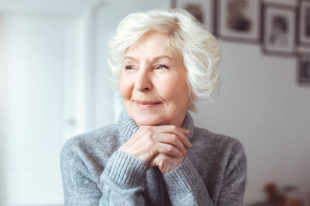 Portrait of handsome grandmother in gray sweater. Dreaming, wondering concept stock photo