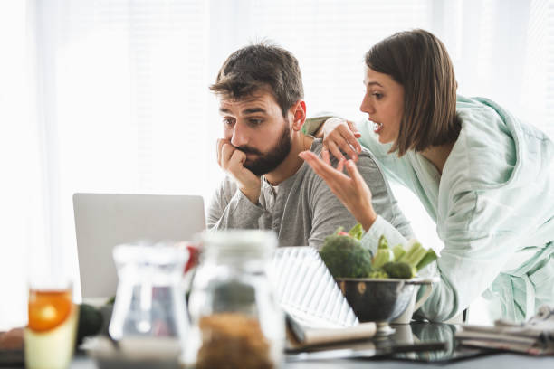 istock Couple using laptop and talking at the kitchen counter 1145944501
