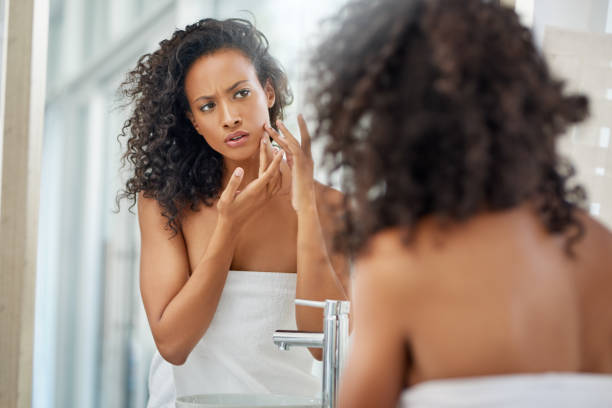 Time for some anti acne cream .Shot of an attractive young woman inspecting her face in the bathroom mirror imperfection stock pictures, royalty-free photos & images