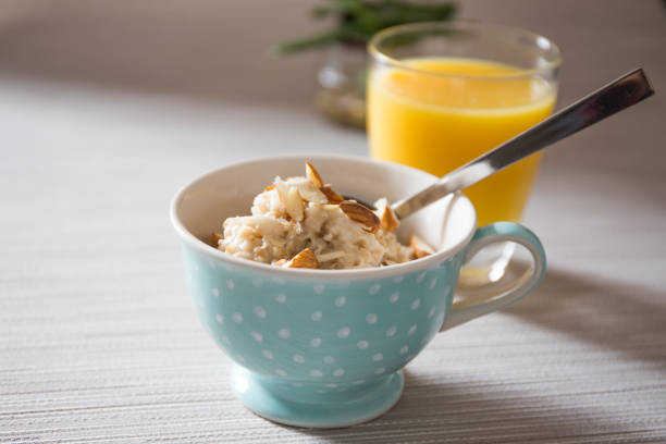 Bowl of homemade oatmeal porridge with almonds and orange juice