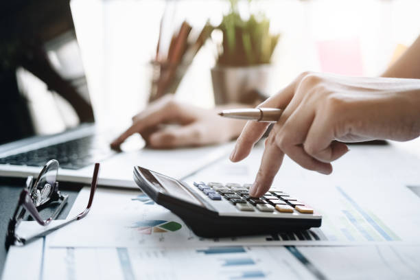 Close up Business woman using calculator and laptop for do math finance on wooden desk in office and business working background, tax, accounting, statistics and analytic research concept close up mujer de negocios usando calculadora y portátil para hacer finanzas matemáticas en el escritorio de madera en la oficina y negocios de fondo de trabajo, impuestos, contabilidad, estadísticas y el concepto de investigación analítica