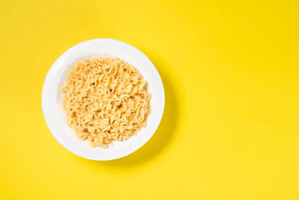 Soup Ramen noodles in ceramic bowl horizontal on a yellow background with copy space.