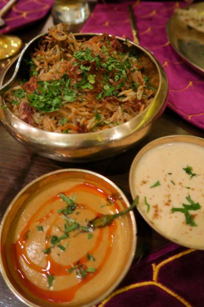 imagen del hombre hindú comiendo pollo lucknowi receta biryani en la cena restaurante indio con platos dorados y thali, salsa de salsa de sherva shorba, raita, pollo biryani basmati foto de arroz, guarnición de cilantro, platos de metal en la mesa en nue - lucknow fotografías e imágenes de stock
