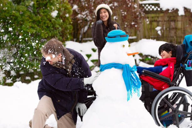istock Father playing snowball fight with disabled son in winter 1145960475