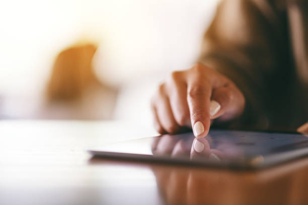 a woman pointing finger at tablet pc on wooden table