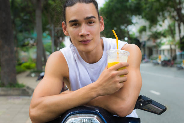 Close portrait of a fit young caucasian man in a tank top holding an orange drink