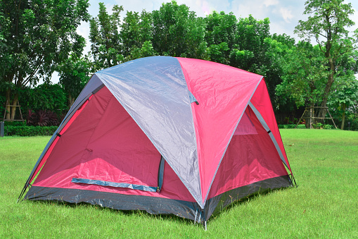 Camping tent on green grass and trees behind.