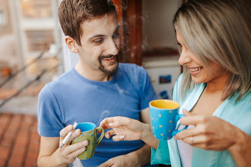 Young loving couple at home drinking coffee at morning near window